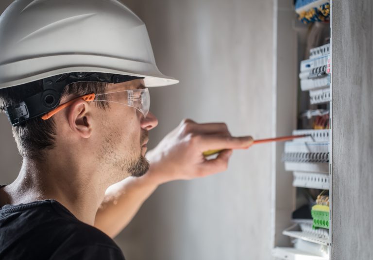 man, an electrical technician working in a switchboard with fuses. Installation and connection of electrical equipment. Close up